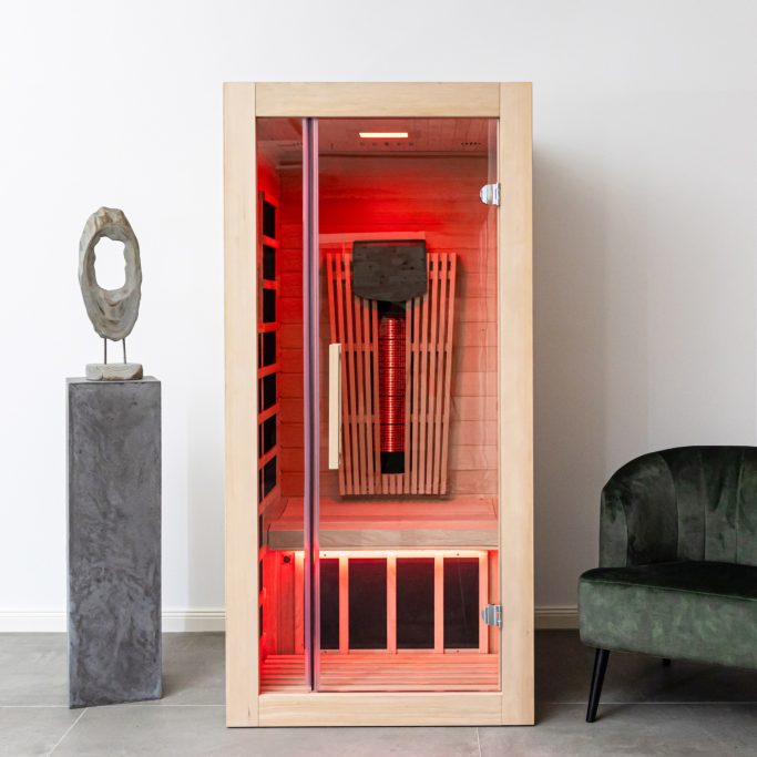 Sauna-Kabine aus Holz mit rotem Licht, daneben eine Skulptur und ein grünes Sofa.